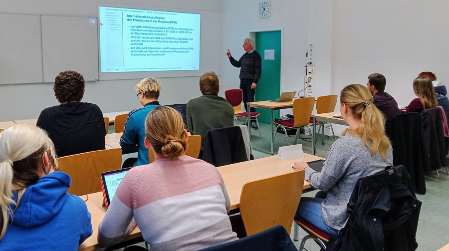 Einblick ins Studium, Raum mit Student:innen, Lehrer und Beamerpräsentation