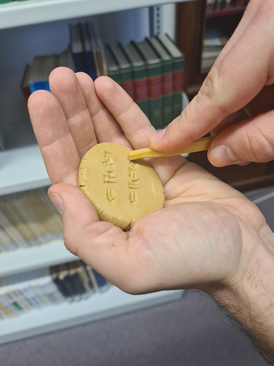 Runde Keilschrifttafel, die in einer Hand liegt.