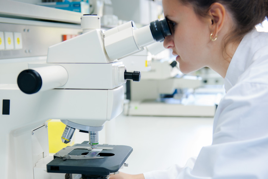 Wissenschaftlerin schaut durch ein Mikroskop